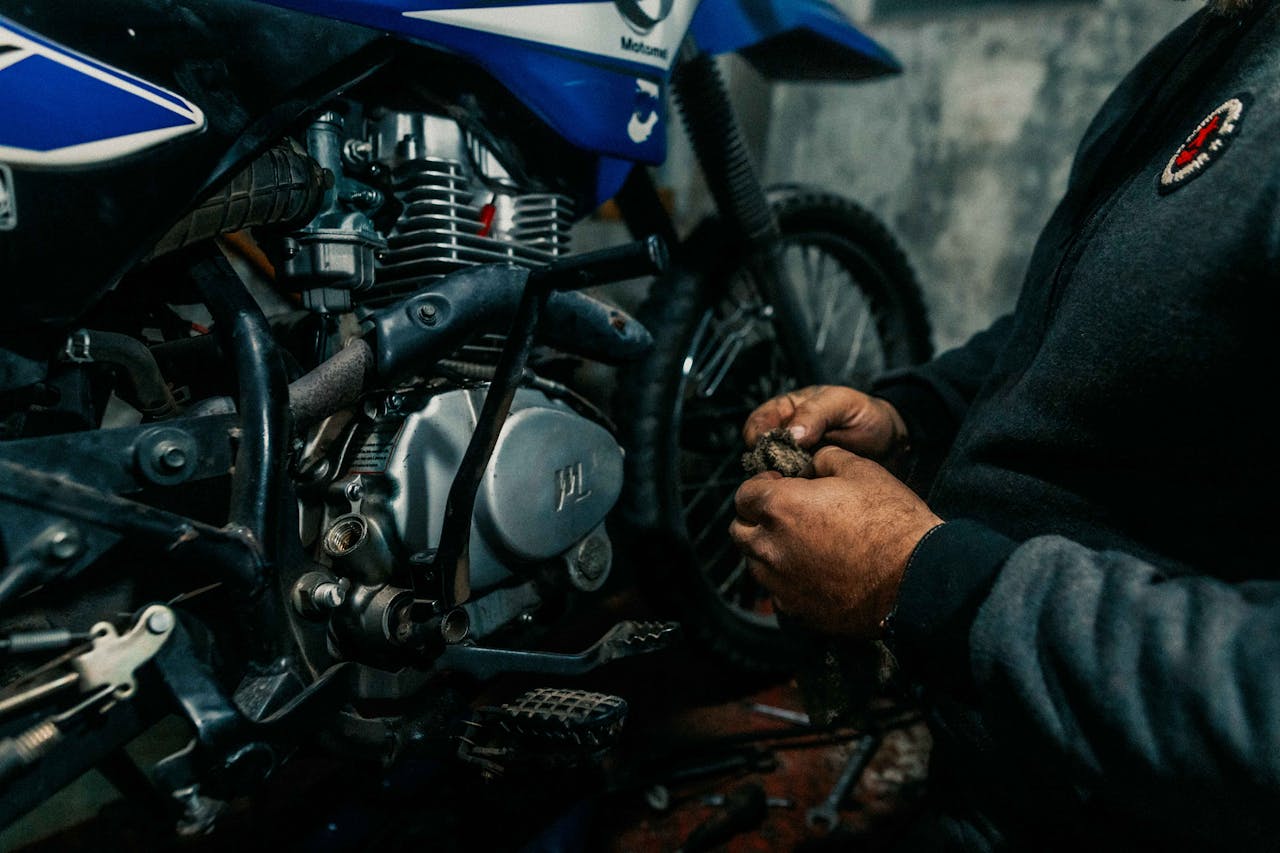 Mechanic works on a motorcycle engine in a garage, focusing on intricate details.