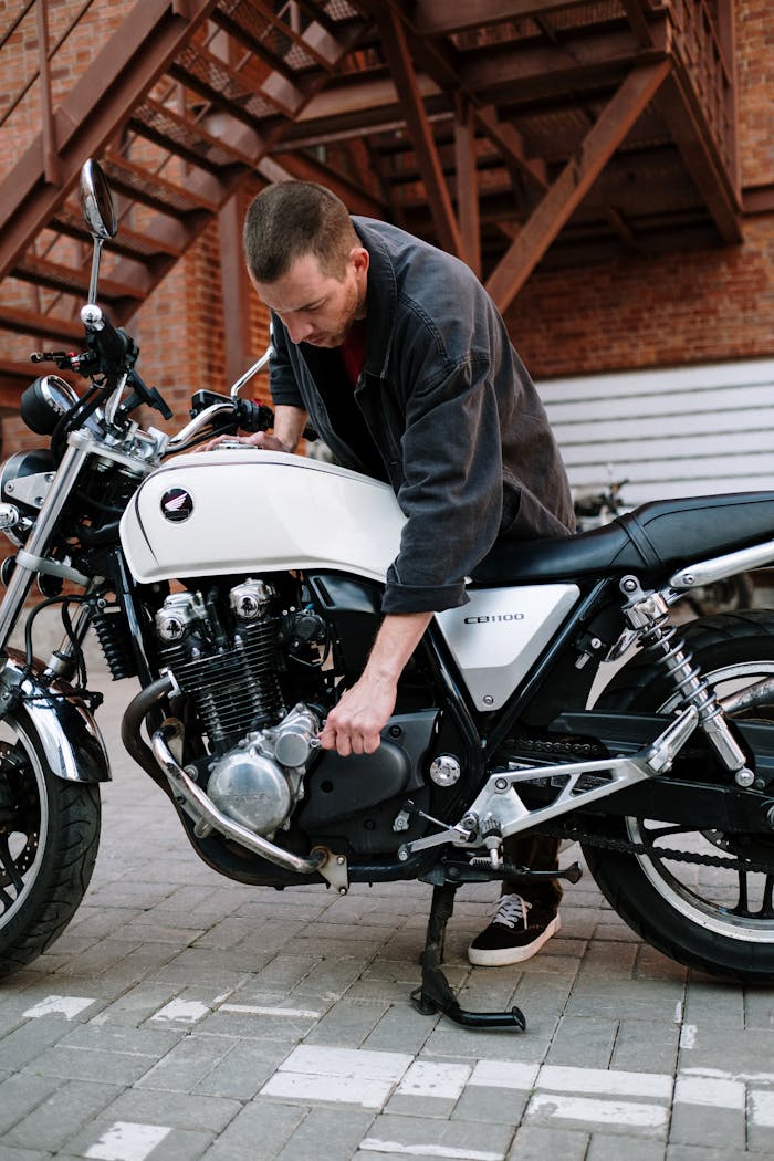 Mechanic working on a Honda CB1100 motorcycle engine outdoors.