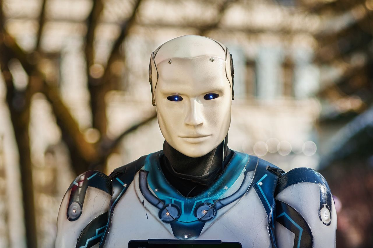 about-02 Close-up of a humanoid robot with a futuristic design posing outdoors.